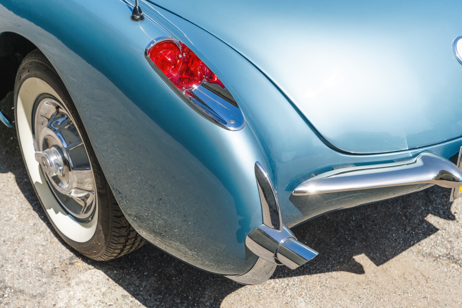 Rear tail light and chrome detail on one side of a light blue 1957 Chevrolet Corvette