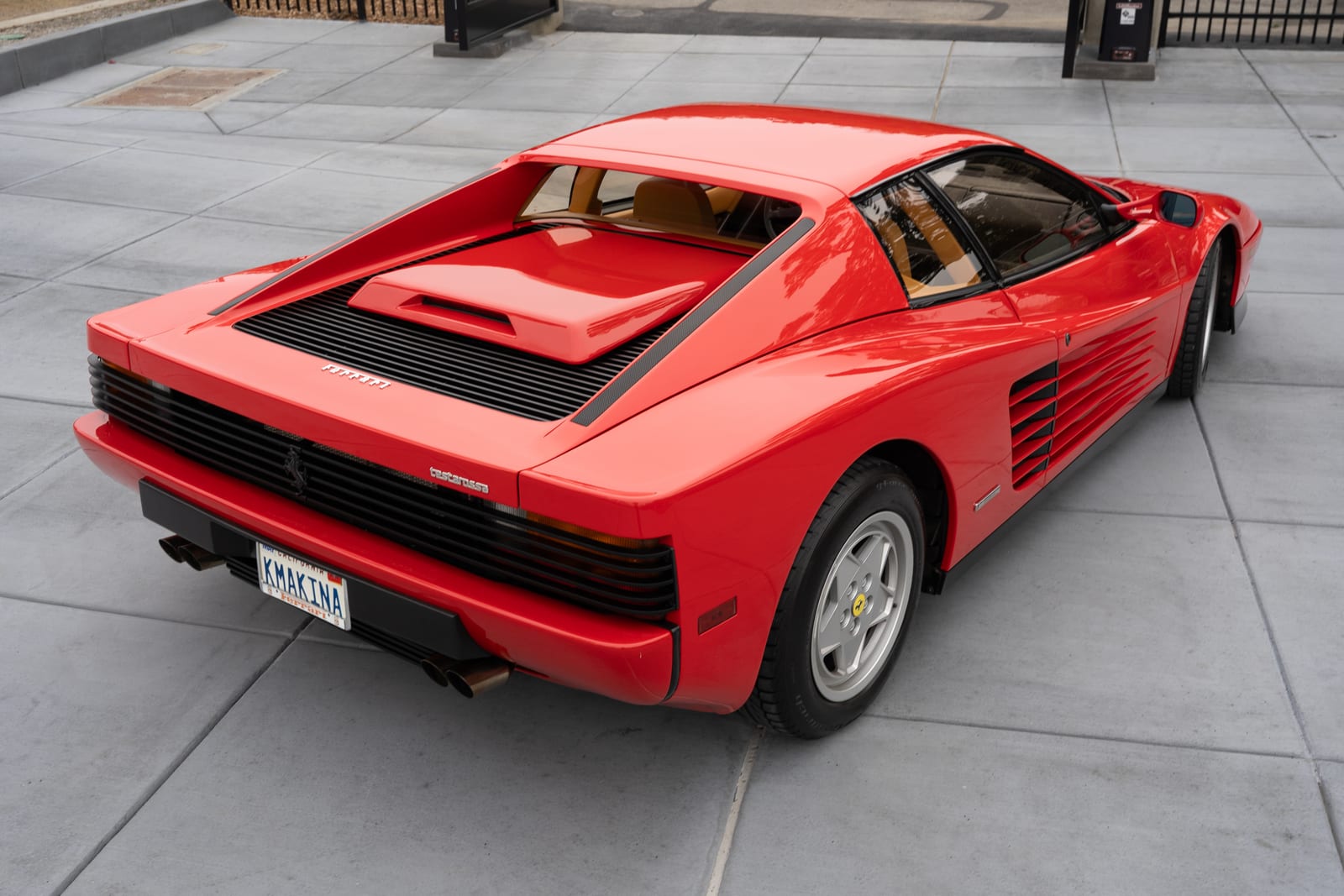 Rear three-quarter view of a red 1990 Ferrari Testarossa from above, the wide tail and rear grille filling the frame