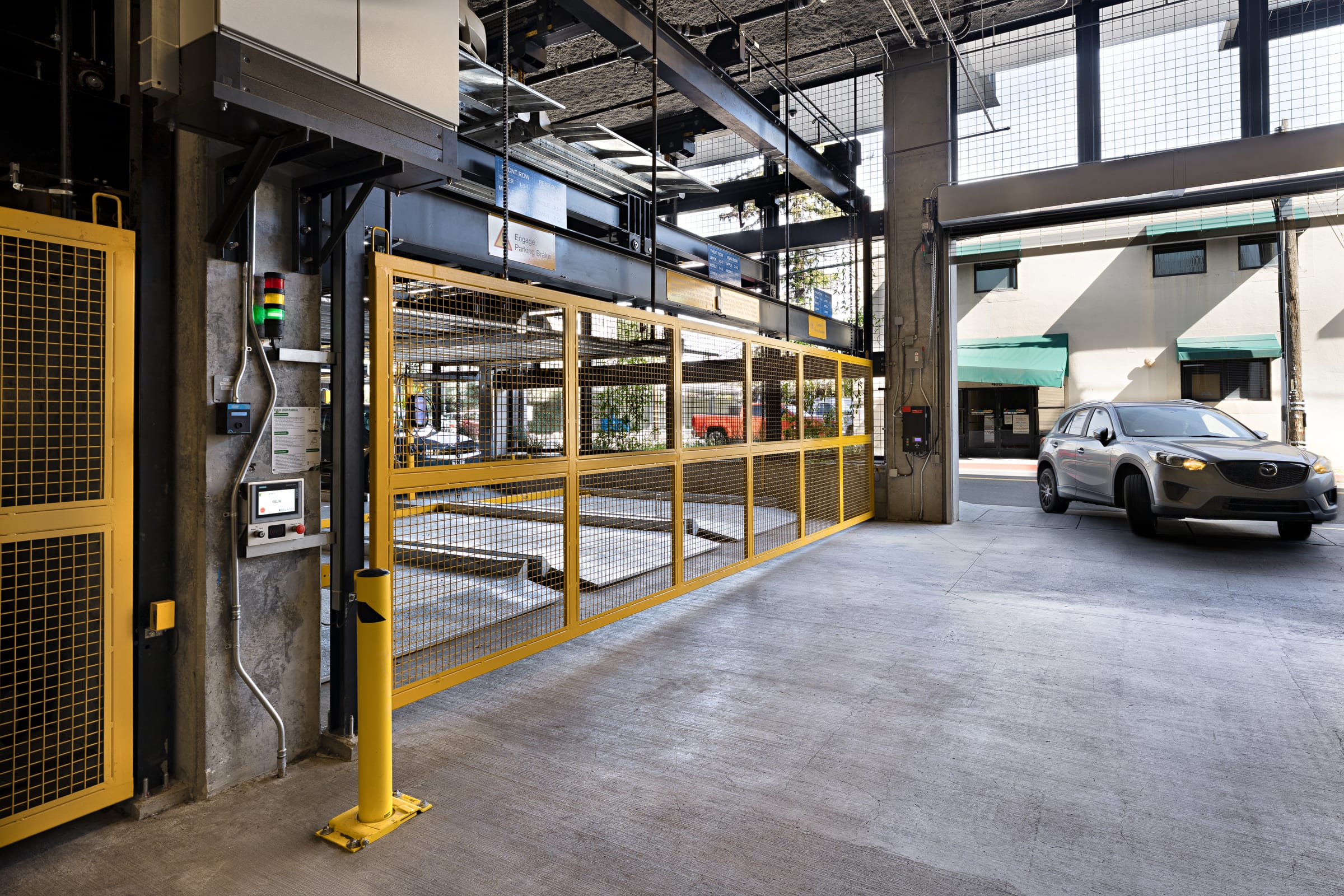 Parkworks automated parking at Felix Apartments: a car entering the garage past the platform guard mesh and control column