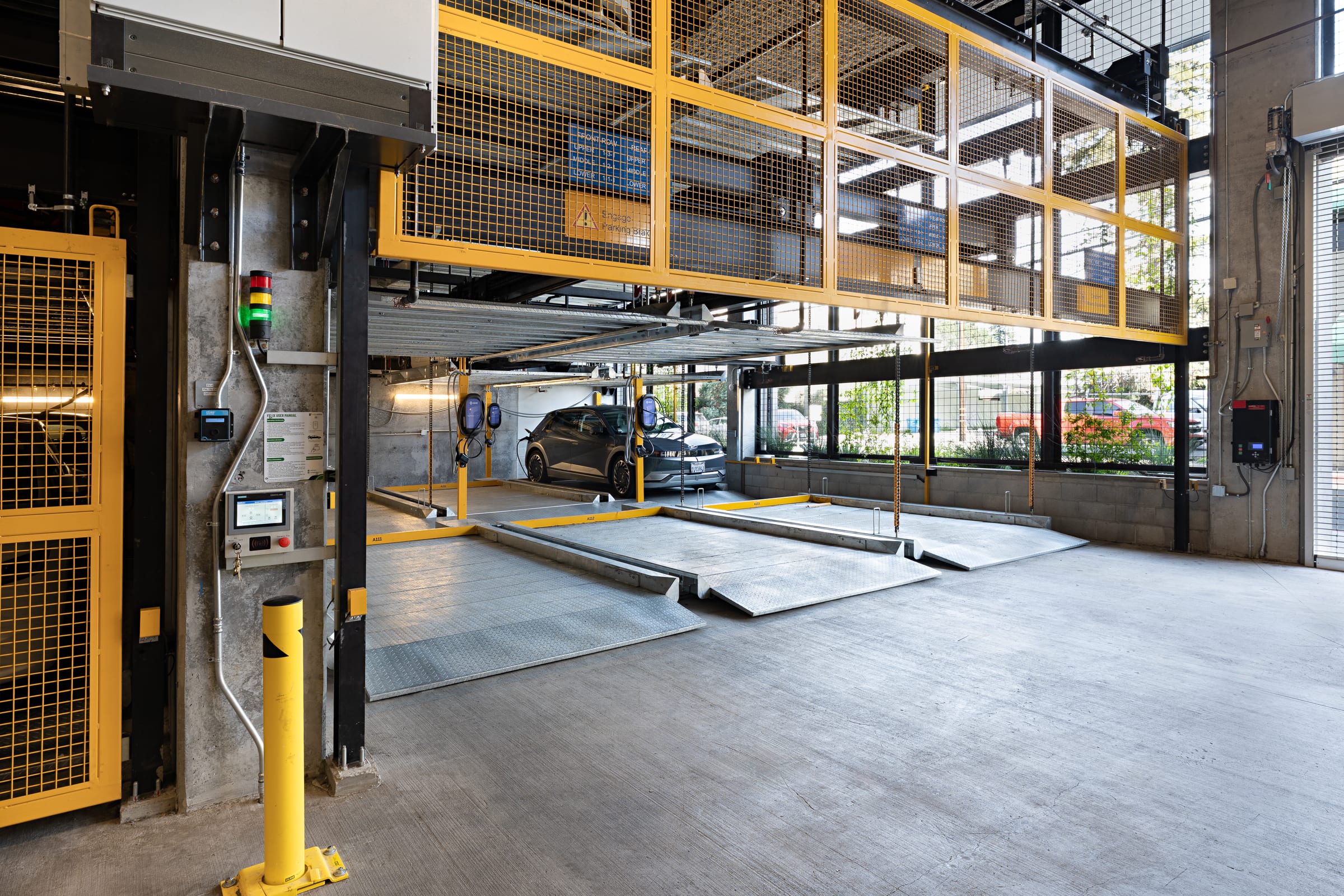Parkworks automated parking system, Felix Apartments Santa Rosa: lift column, safety guard and status lights beside a parked car