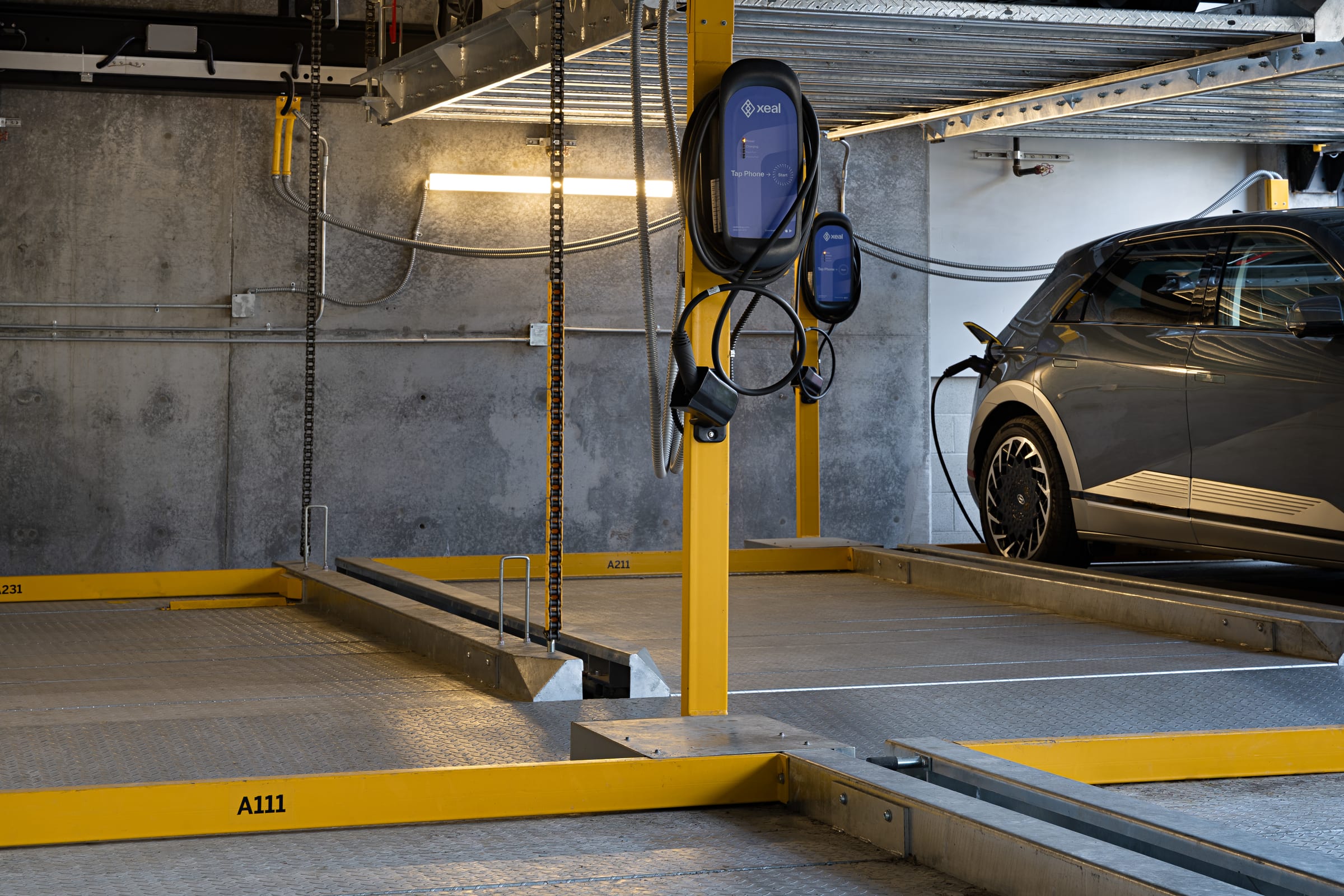 Parkworks automated parking at Felix Apartments: an electric car on a lift platform with a wall-mounted EV charger